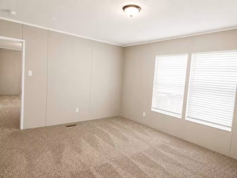 Empty room with beige walls, carpet, two windows with white blinds, and ceiling light fixture