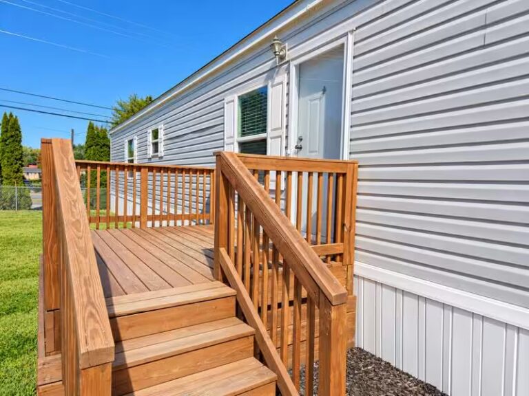 Wooden deck stairs leading to a white-sided house with white door.