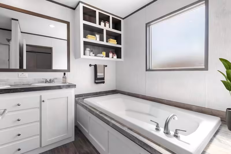 Modern bathroom with white bathtub, vanity, mirror, shelving with towels, and bright window.